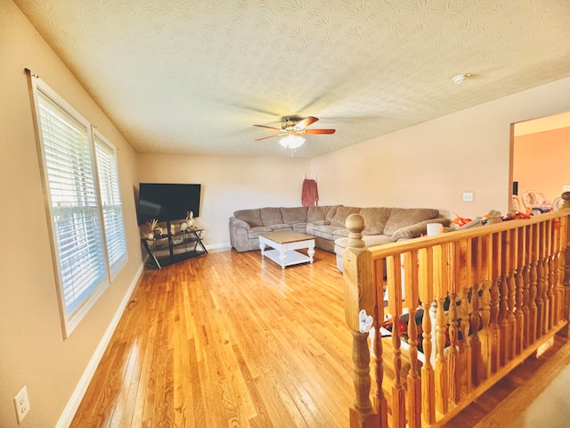 living room featuring ceiling fan, a textured ceiling, and hardwood / wood-style floors