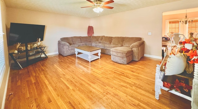 living room with ceiling fan with notable chandelier, hardwood / wood-style floors, and a textured ceiling