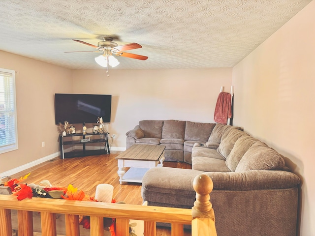 living room featuring ceiling fan, hardwood / wood-style floors, and a textured ceiling