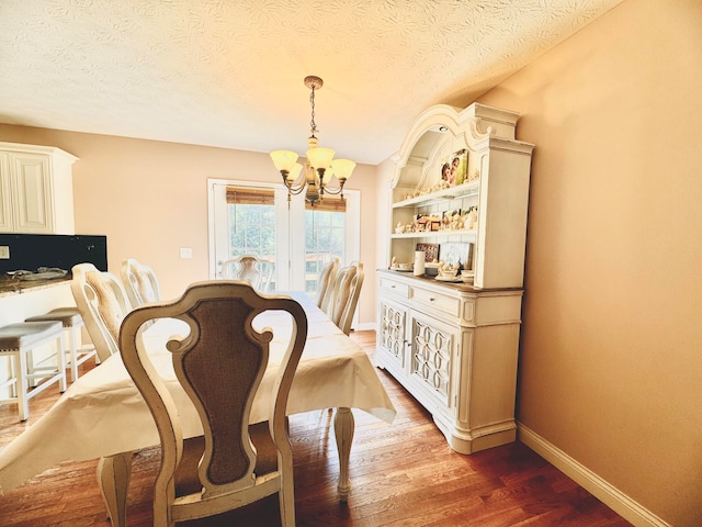 dining area featuring a notable chandelier, dark wood-type flooring, and a textured ceiling