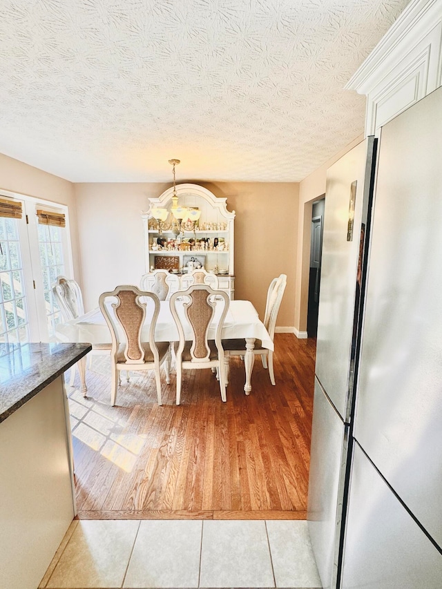 dining area with light hardwood / wood-style flooring and a textured ceiling