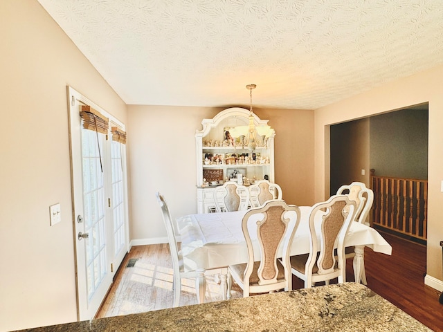 dining room with hardwood / wood-style floors and a textured ceiling