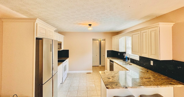 kitchen featuring kitchen peninsula, stone counters, sink, and stainless steel appliances