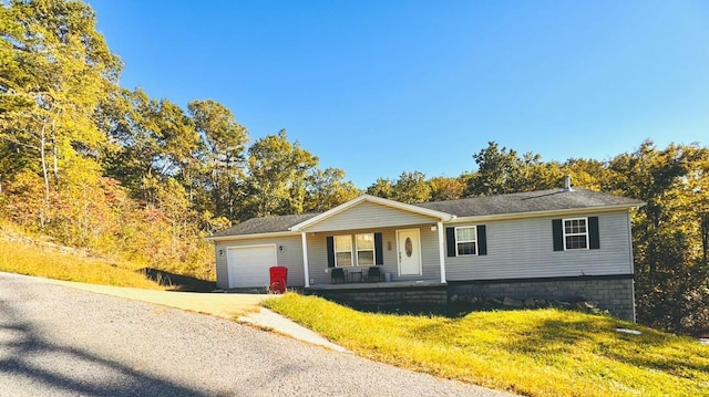 view of front of home with covered porch, a front yard, and a garage