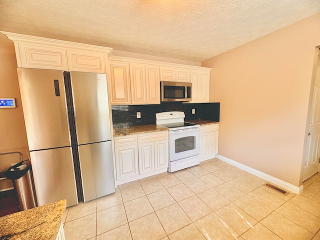 kitchen with light stone counters, stainless steel appliances, light tile patterned floors, and decorative backsplash