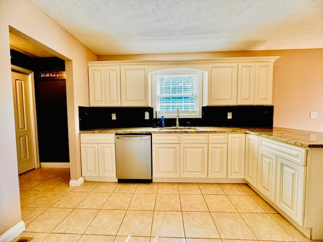 kitchen with light tile patterned floors, sink, stainless steel dishwasher, a textured ceiling, and backsplash