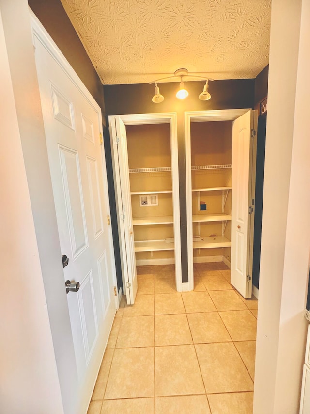 hall featuring light tile patterned flooring and a textured ceiling