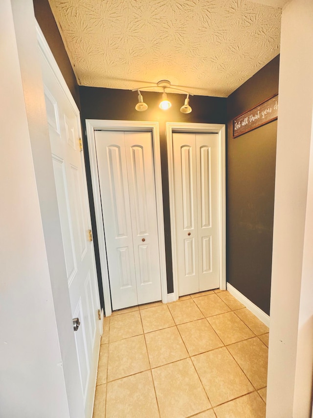 hall featuring light tile patterned floors and a textured ceiling