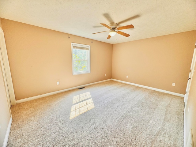 carpeted empty room with ceiling fan and a textured ceiling