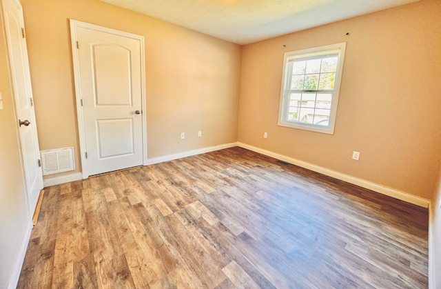 spare room featuring a textured ceiling and light hardwood / wood-style floors