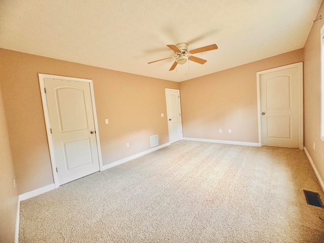 empty room featuring ceiling fan, a textured ceiling, and carpet