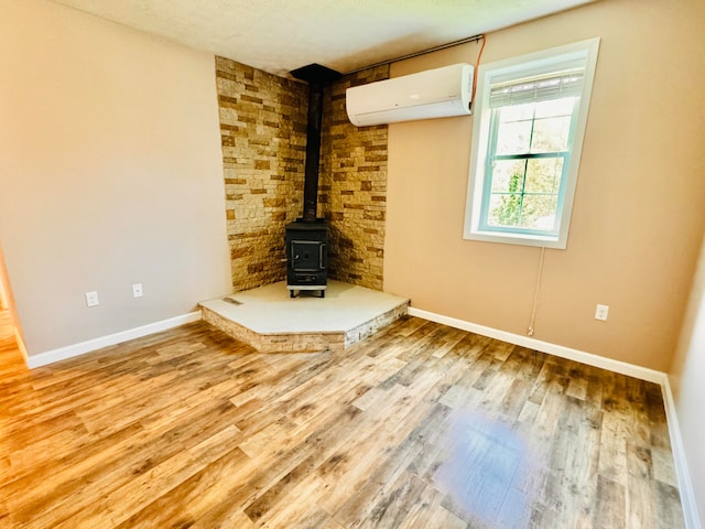 unfurnished living room with a wall mounted air conditioner, hardwood / wood-style floors, and a textured ceiling