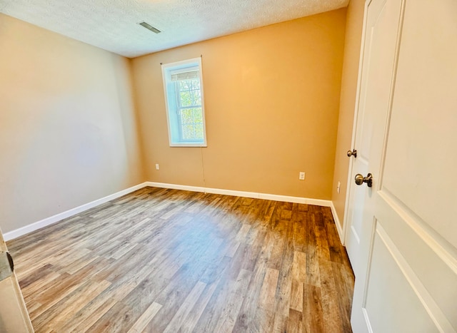 empty room with hardwood / wood-style floors and a textured ceiling