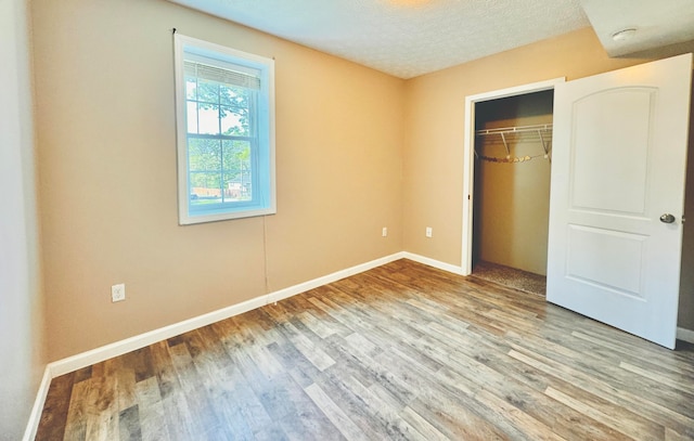 unfurnished bedroom with a closet, wood-type flooring, and a textured ceiling