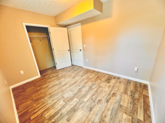 unfurnished bedroom with light wood-type flooring, a closet, and a textured ceiling