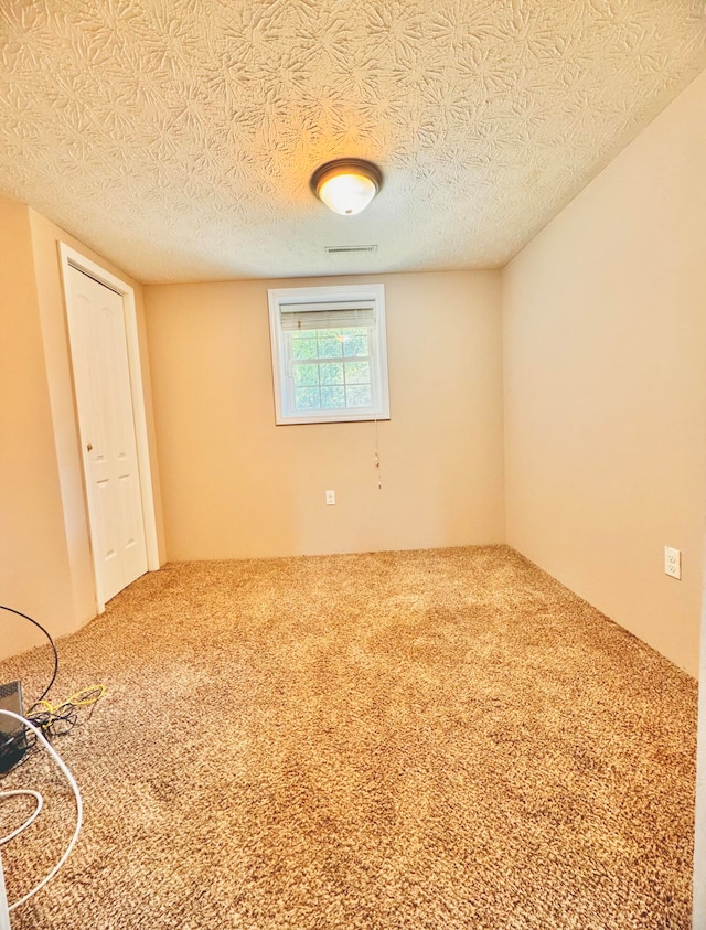 empty room with carpet floors and a textured ceiling