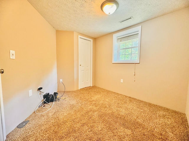 unfurnished room featuring a textured ceiling and carpet