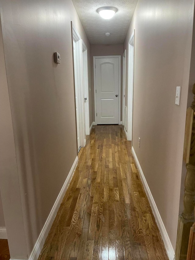 corridor with wood-type flooring and a textured ceiling