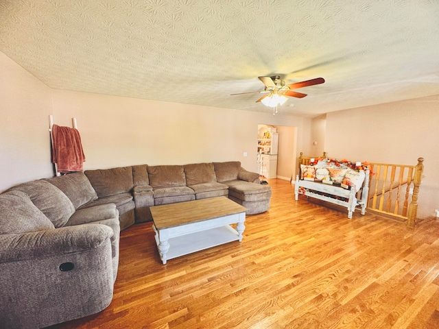 living room with ceiling fan, hardwood / wood-style flooring, and a textured ceiling