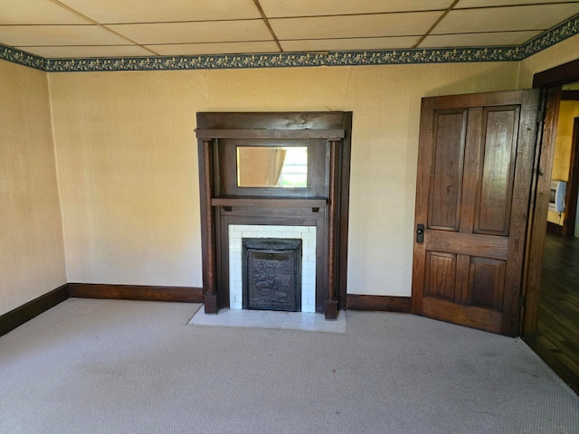 unfurnished living room featuring carpet floors and a drop ceiling