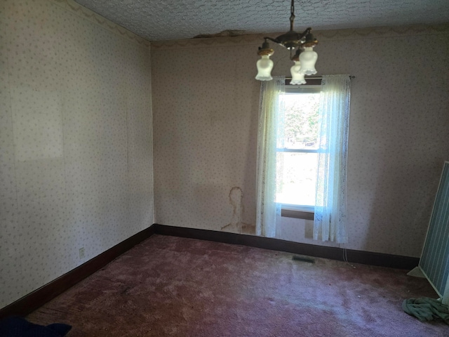 empty room featuring carpet floors, a chandelier, and a textured ceiling