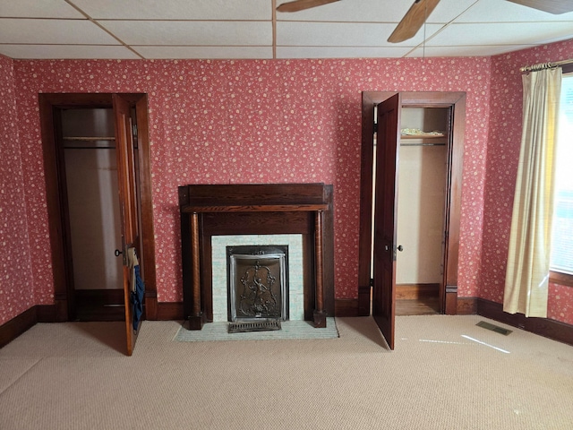 unfurnished living room featuring a paneled ceiling, carpet, a fireplace, and a healthy amount of sunlight