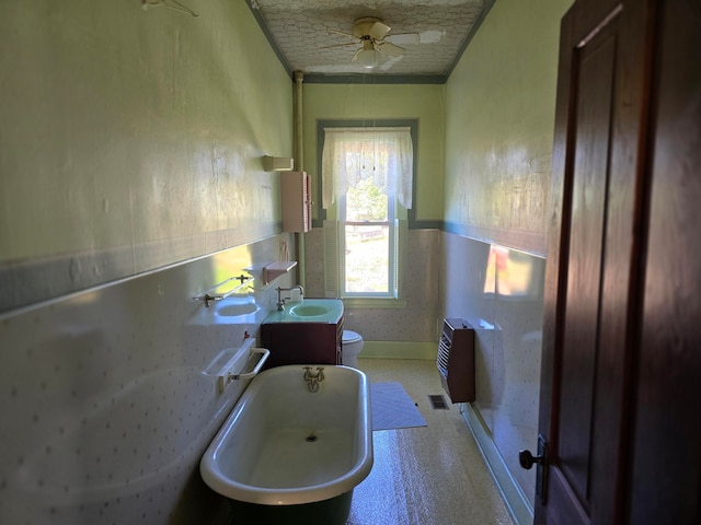 bathroom featuring ceiling fan, vanity, a tub, a textured ceiling, and toilet