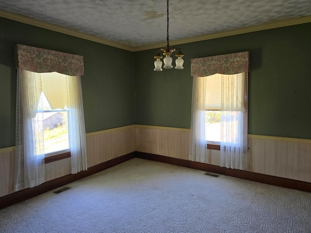 carpeted spare room with a textured ceiling, wooden walls, and a notable chandelier