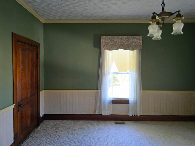 spare room featuring an inviting chandelier, wooden walls, crown molding, and a textured ceiling