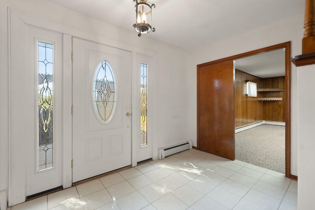 entrance foyer with wooden walls, baseboard heating, and light tile patterned floors