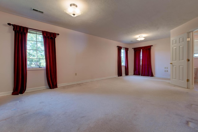 carpeted empty room with a textured ceiling