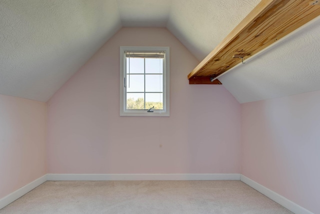 additional living space featuring lofted ceiling, light colored carpet, and a textured ceiling