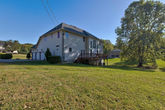 rear view of property featuring a lawn, a wooden deck, and a garage