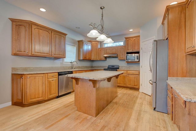 kitchen with a wealth of natural light, light hardwood / wood-style flooring, a kitchen island, and appliances with stainless steel finishes