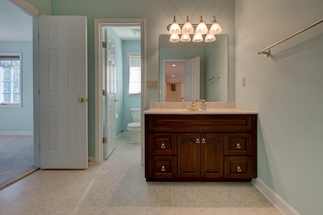 bathroom with tile patterned flooring, vanity, toilet, and a healthy amount of sunlight