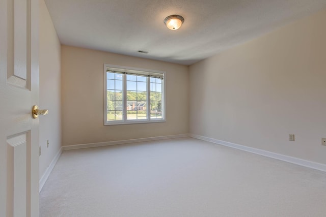 spare room featuring a textured ceiling and light carpet