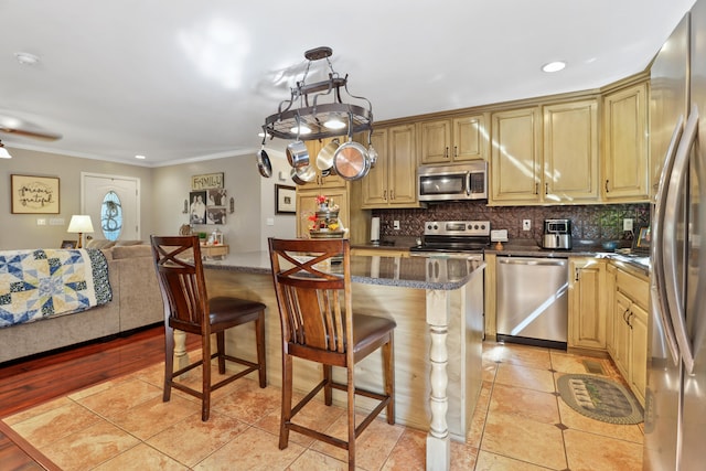 kitchen with stainless steel appliances, light hardwood / wood-style flooring, backsplash, crown molding, and a breakfast bar