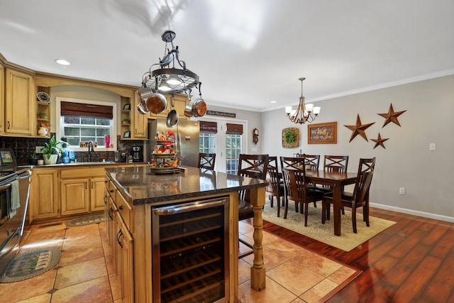 kitchen featuring beverage cooler, an inviting chandelier, ornamental molding, a kitchen island, and light wood-type flooring