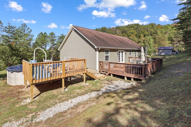 rear view of house with a lawn, a swimming pool side deck, and a storage unit