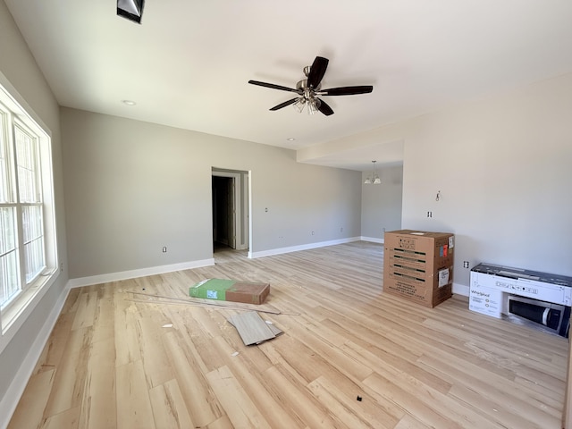 unfurnished living room with ceiling fan with notable chandelier and wood-type flooring