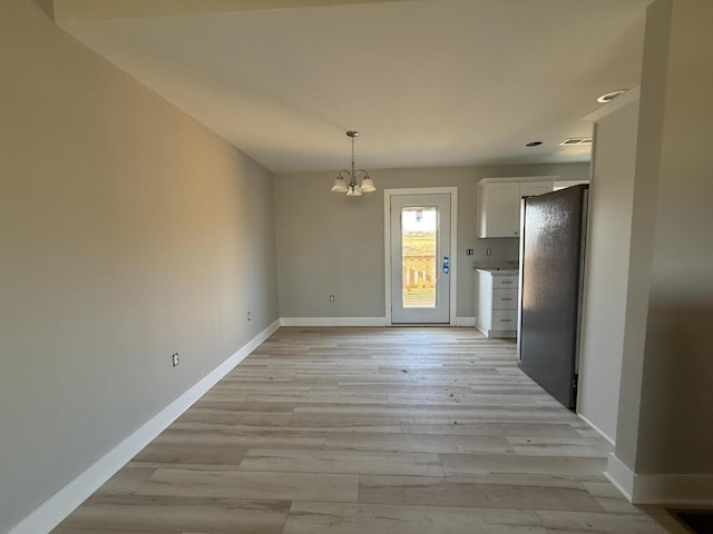 unfurnished dining area featuring light hardwood / wood-style flooring and a notable chandelier