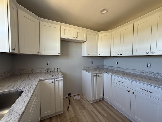 kitchen featuring white cabinets and light stone countertops