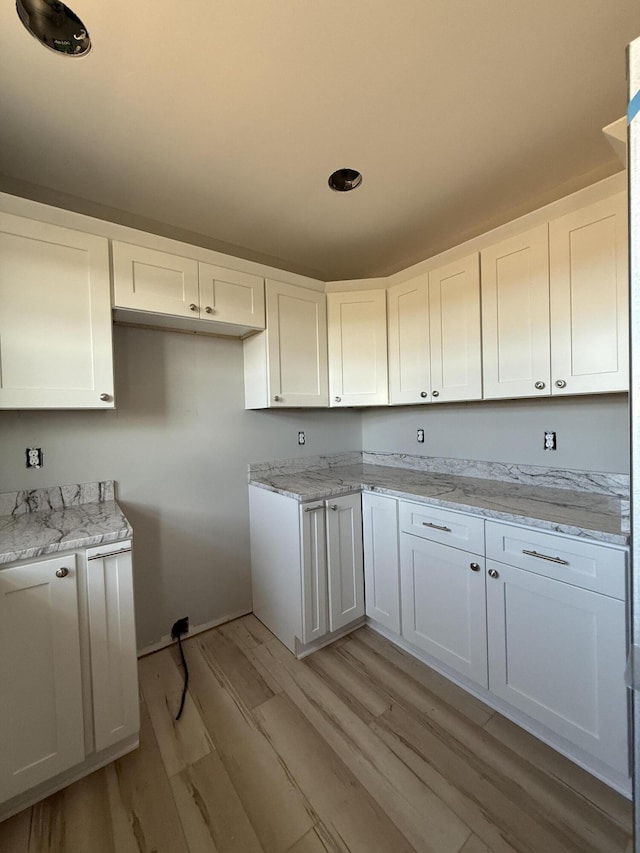 kitchen featuring white cabinets, light hardwood / wood-style flooring, and light stone counters