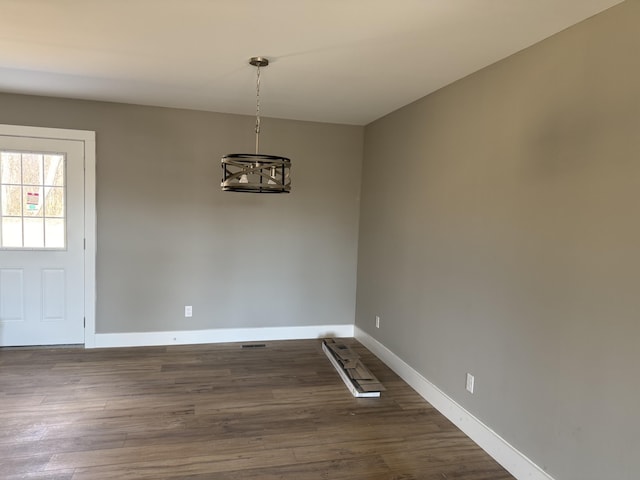 unfurnished dining area featuring baseboards and dark wood finished floors