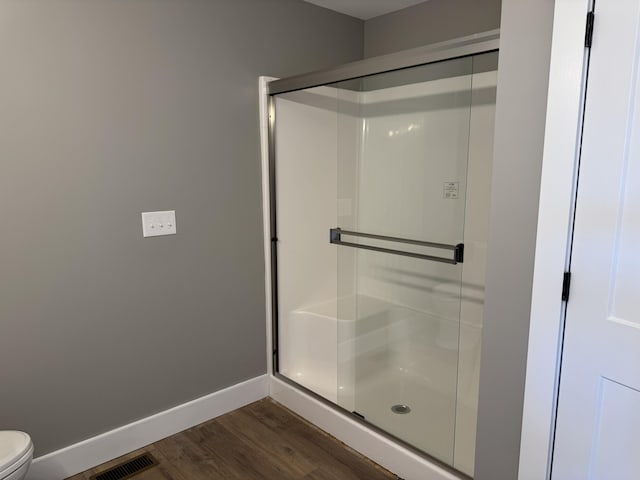 full bath featuring a stall shower, baseboards, visible vents, and wood finished floors