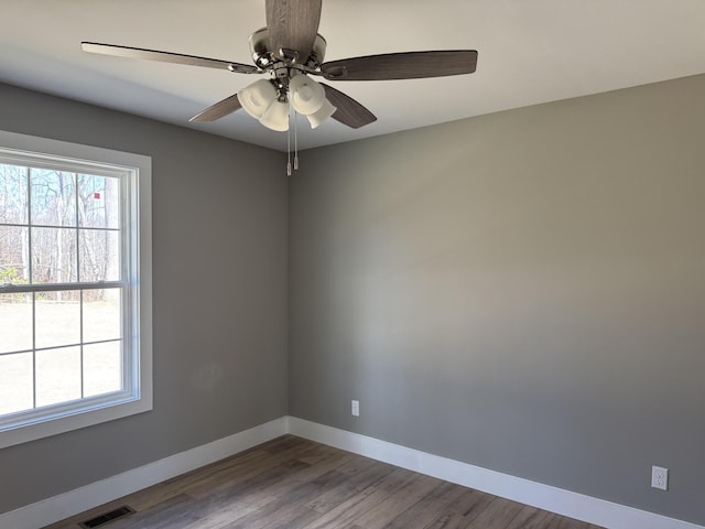 unfurnished room featuring a ceiling fan, baseboards, visible vents, and wood finished floors