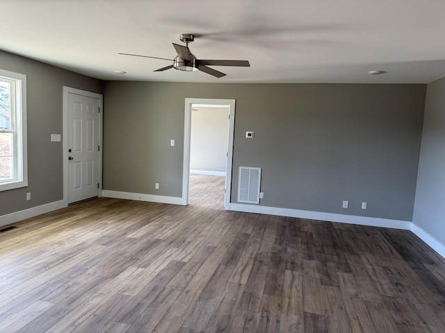 unfurnished room with dark wood-style floors, ceiling fan, visible vents, and baseboards