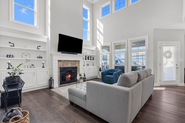 living room featuring built in shelves, a high ceiling, dark wood-type flooring, and a healthy amount of sunlight