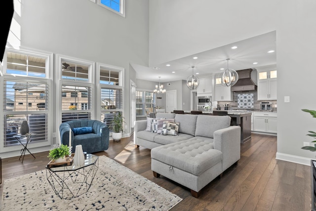 living room featuring dark wood-type flooring, a high ceiling, and a notable chandelier