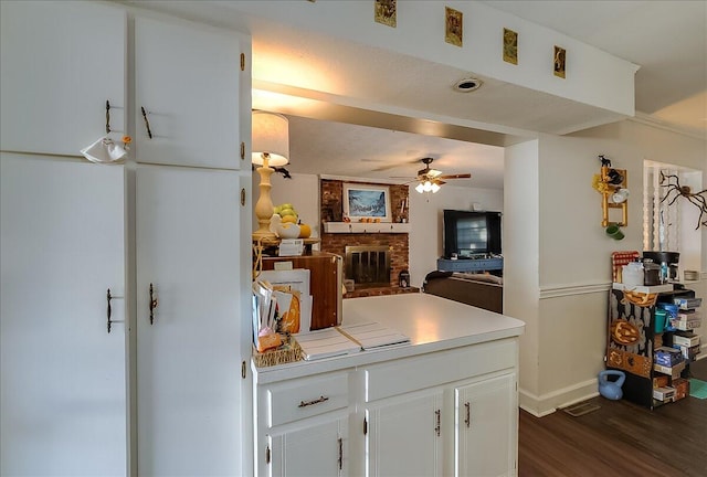 kitchen with a fireplace, ceiling fan, dark wood-type flooring, and white cabinets